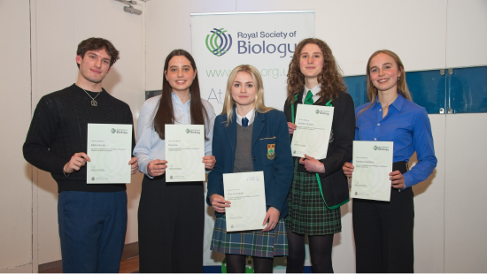 School students standing side by side in front of RSB banner holding their certificates